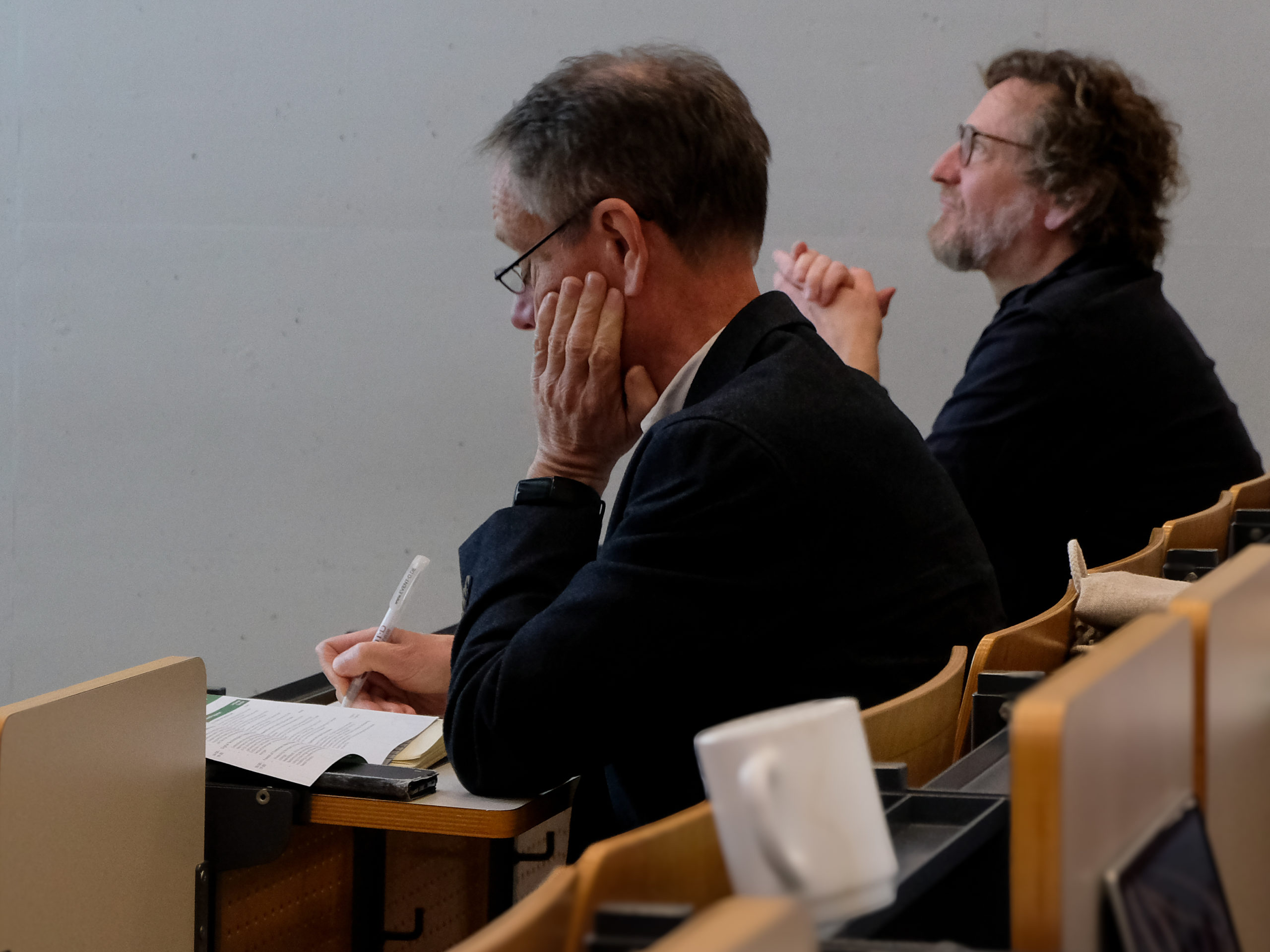 Dr. Werner Rammer and Prof Dr. Martin Ziesak are seen in profile as they listen to a presentation in the main session lecture hall of SmartForest 2025