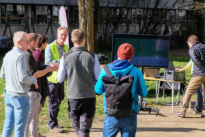 Martin Roth welcomes people to the WOOD.IN.VISION outdoor session during SmartForest 2026, for which a large television has been put on the lawn