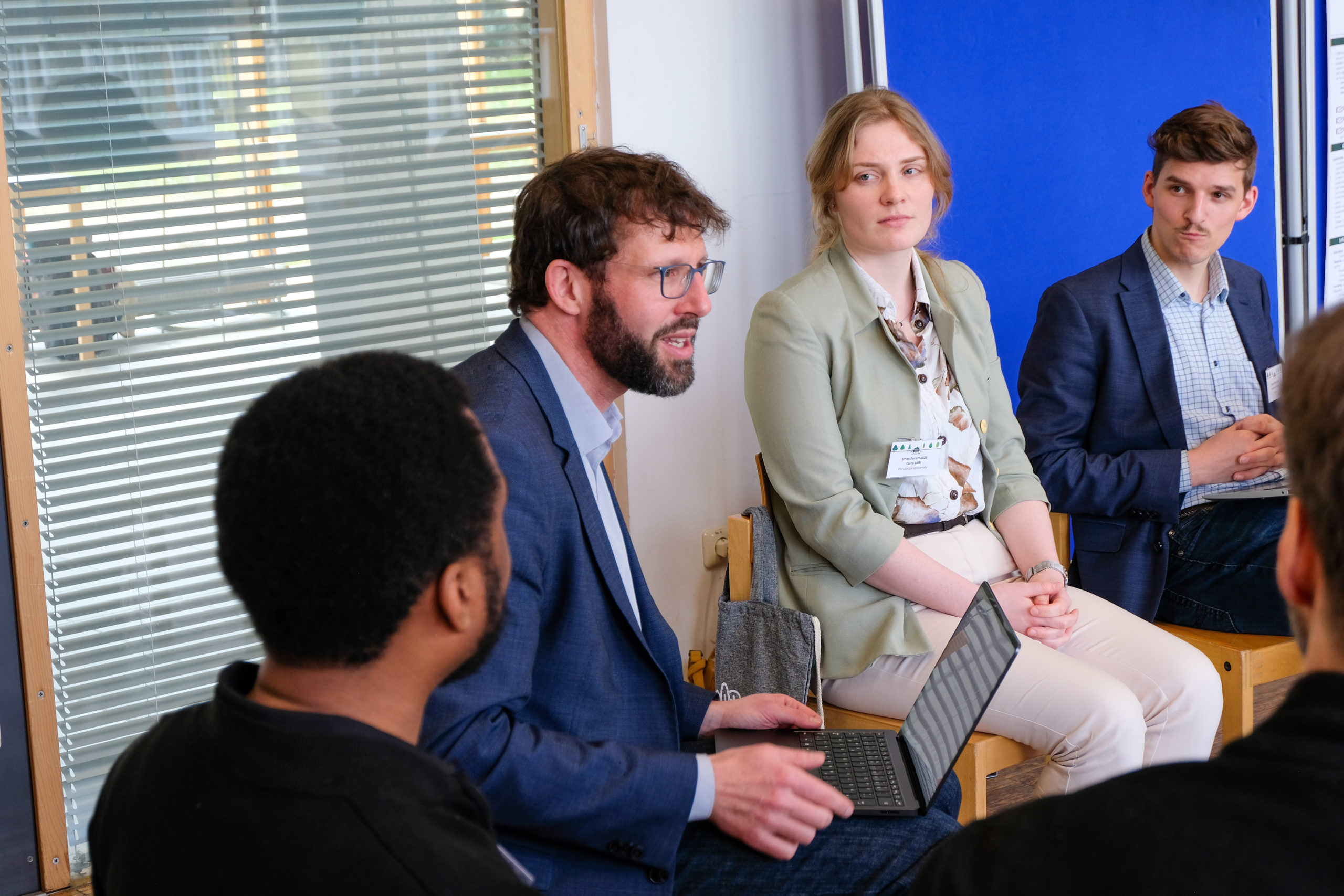 wetransform CEO Thorsten Reitz sits with a laptop on his knees, engaged in discussion with a circle of other participants at SmartForest 2026.