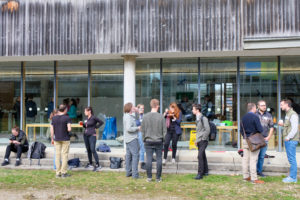 A few groups of people stand about chatting, eating, and drinking during the forestry conference SmartForest 2026, at the TU Munich's campus in Freising.