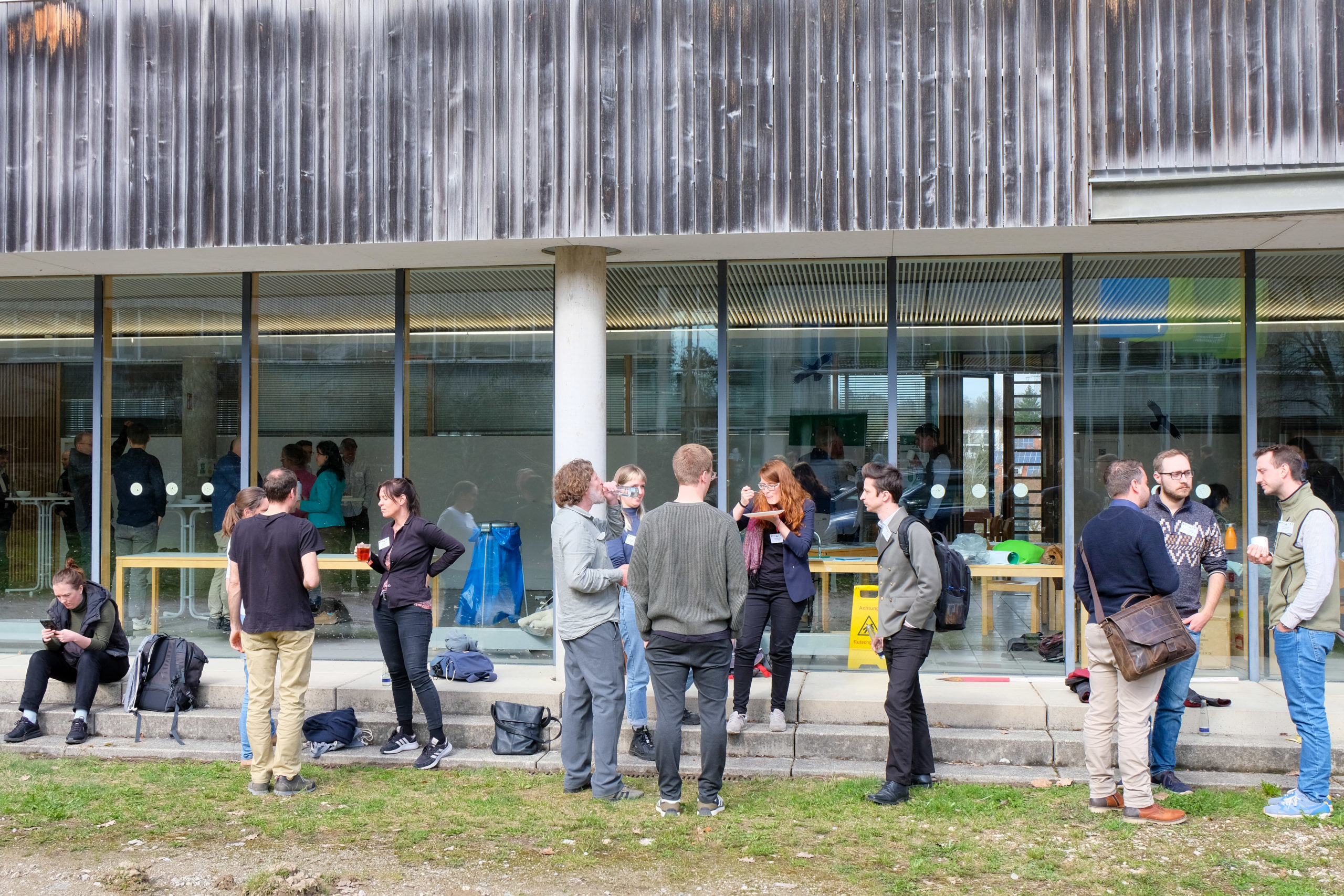 A few groups of people stand about chatting, eating, and drinking during the forestry conference SmartForest 2026, at the TU Munich's campus in Freising.