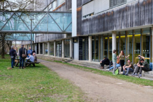 People sit on picnic benches and steps outside the TU Munich's building in Freising, engaged in various discussions during SmartForest 2026.
