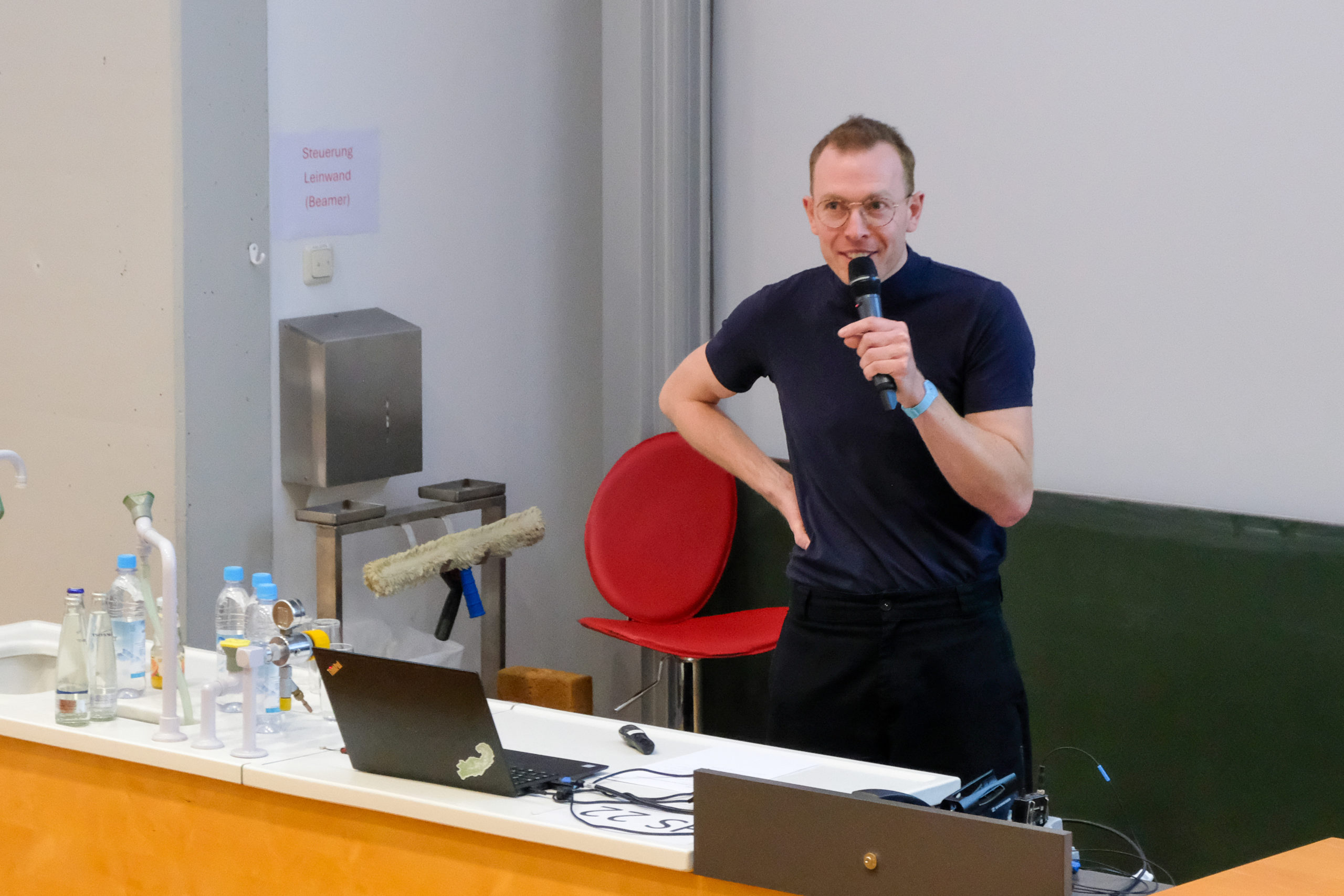 A speaker at SmartForest 2026 stands behind the lectern, hand on hip, addressing the crowd