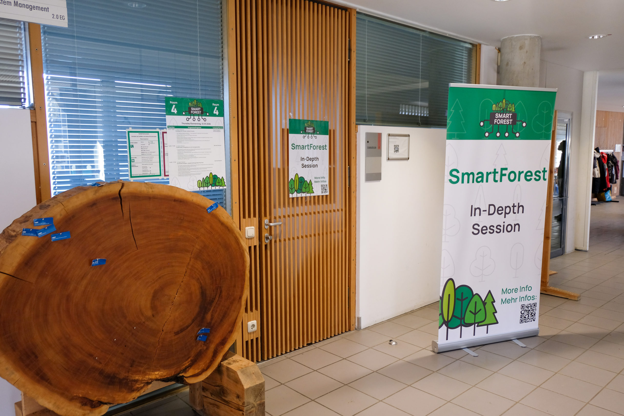 The door to the SmartForest 2026 In-Depth sessions is beside a large mounted cross-section of a tree.