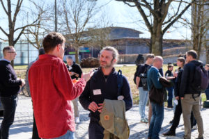 Stefano Puliti of Nibio talks to another attendee outside of SmartForest 2026. Around them, others are also taking advantage of the nice weather to chat in pairs or small groups.