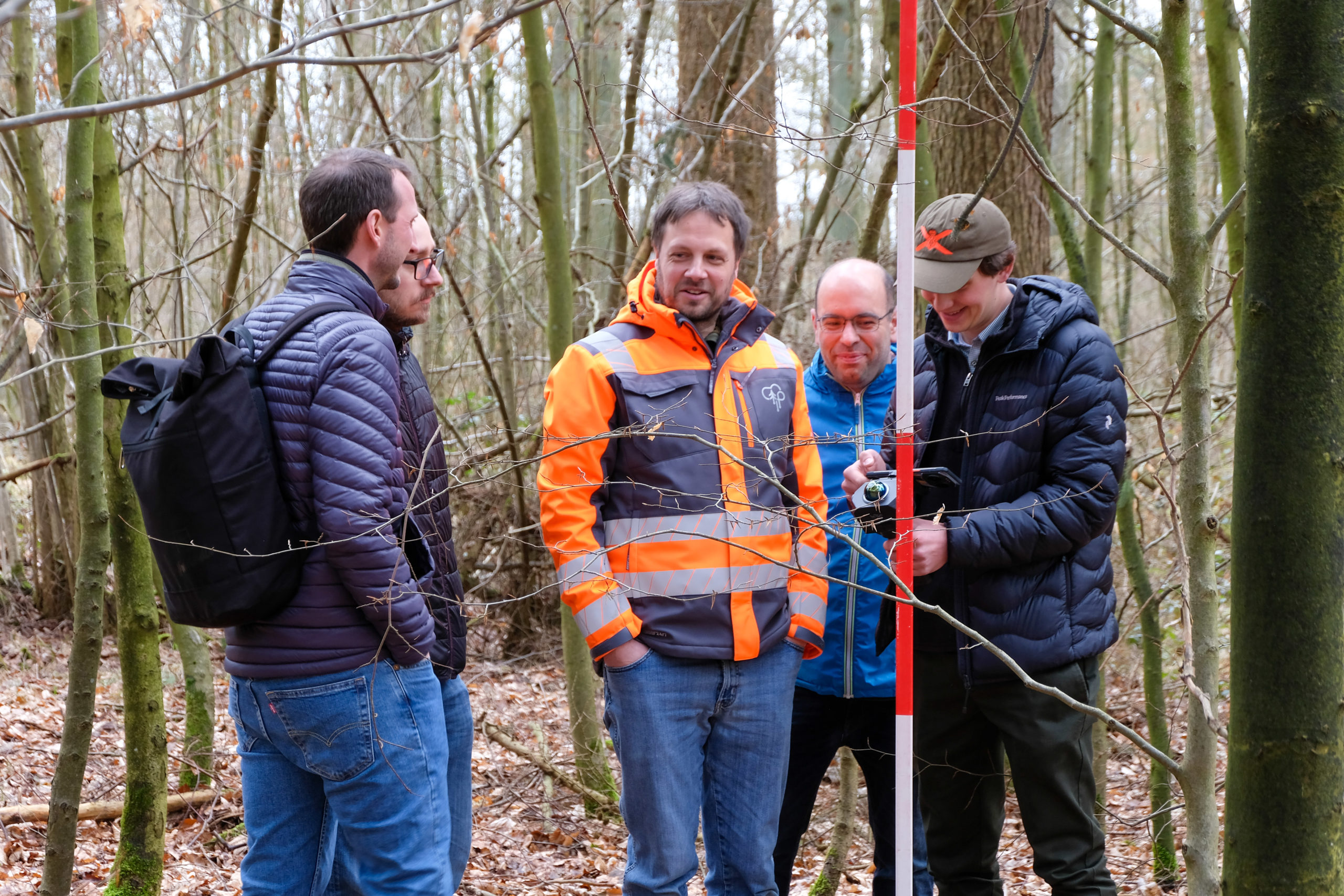 Participants of a SmartForest 2026 outdoor session have a chat in the woods as tree scanning technology is being demonstrated.