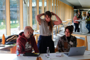 Franziska Hochenegger ties back her hair as she checks a laptop at the SmartForest 2026 reception desk. She is flanked by wetransform colleagues Ronald Kilian and Ramona Resch.