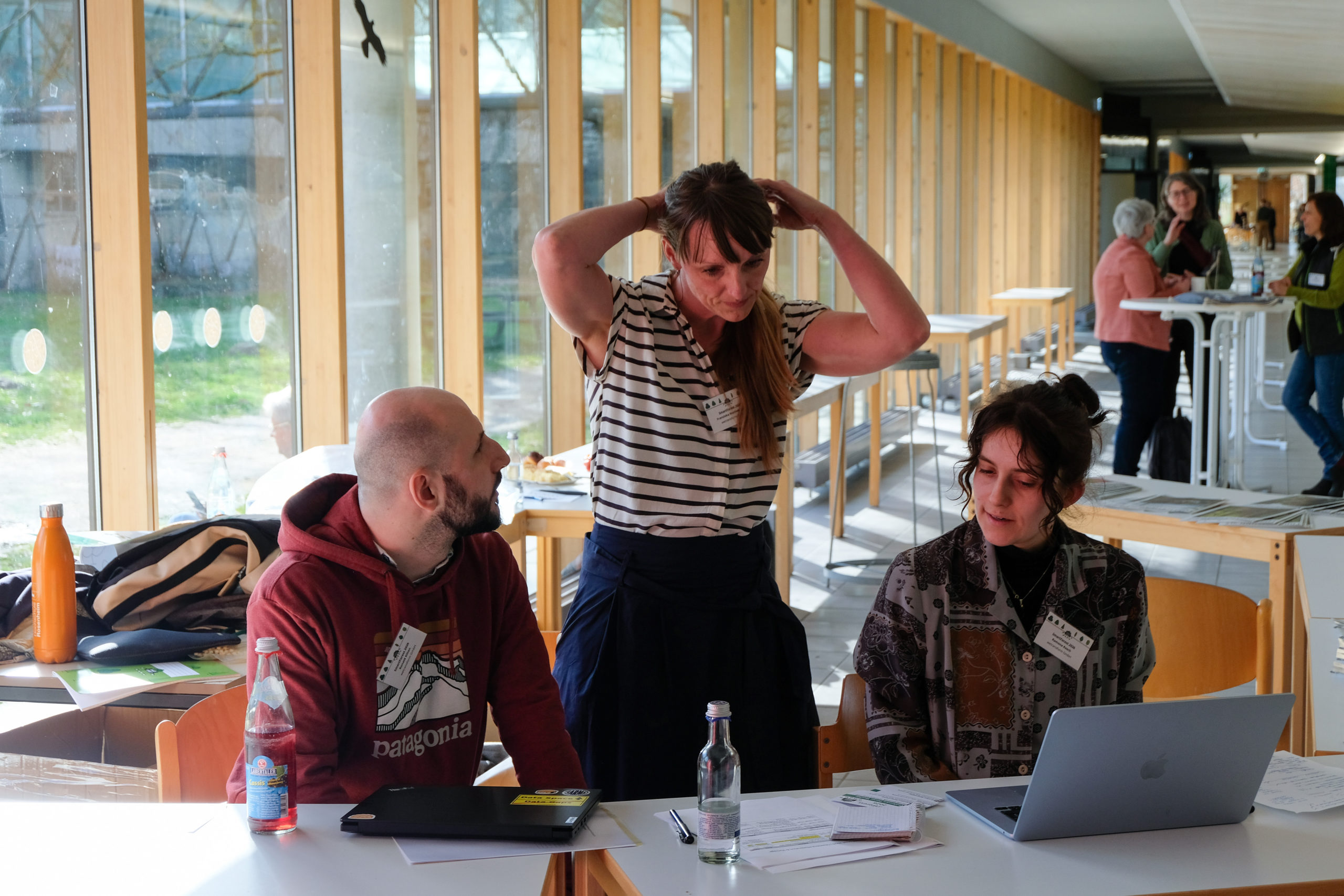 Franziska Hochenegger ties back her hair as she checks a laptop at the SmartForest 2026 reception desk. She is flanked by wetransform colleagues Ronald Kilian and Ramona Resch.