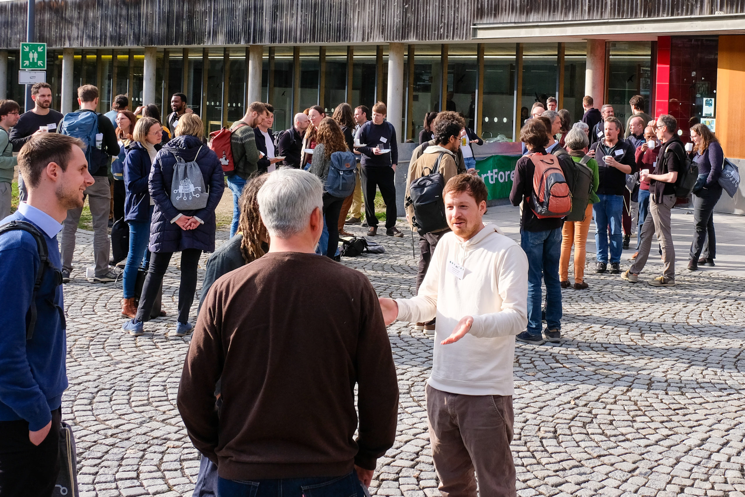 Many attendees of SmartForest 2026 stand outside the conference building, chatting in small groups.