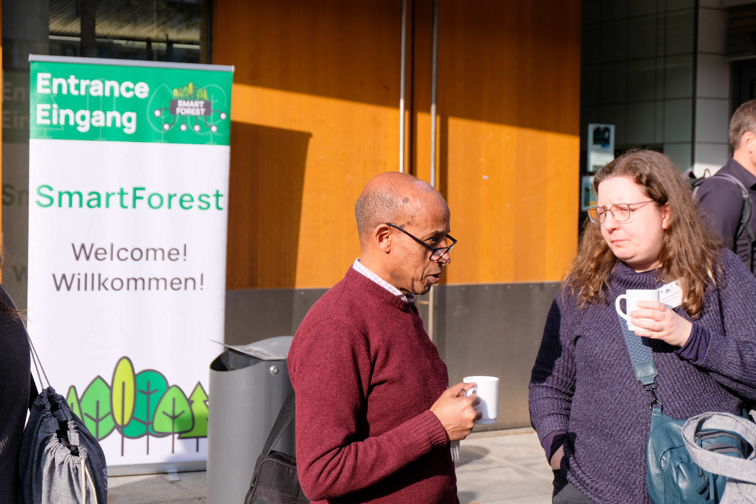 A pair of SmartForest 2026 attendees chats beside the conference's welcome banner