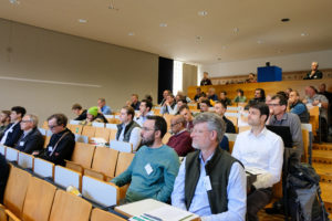A crowd of people listens attentively as they sit on wood-and-metal auditorium seating at SmartForest 2026