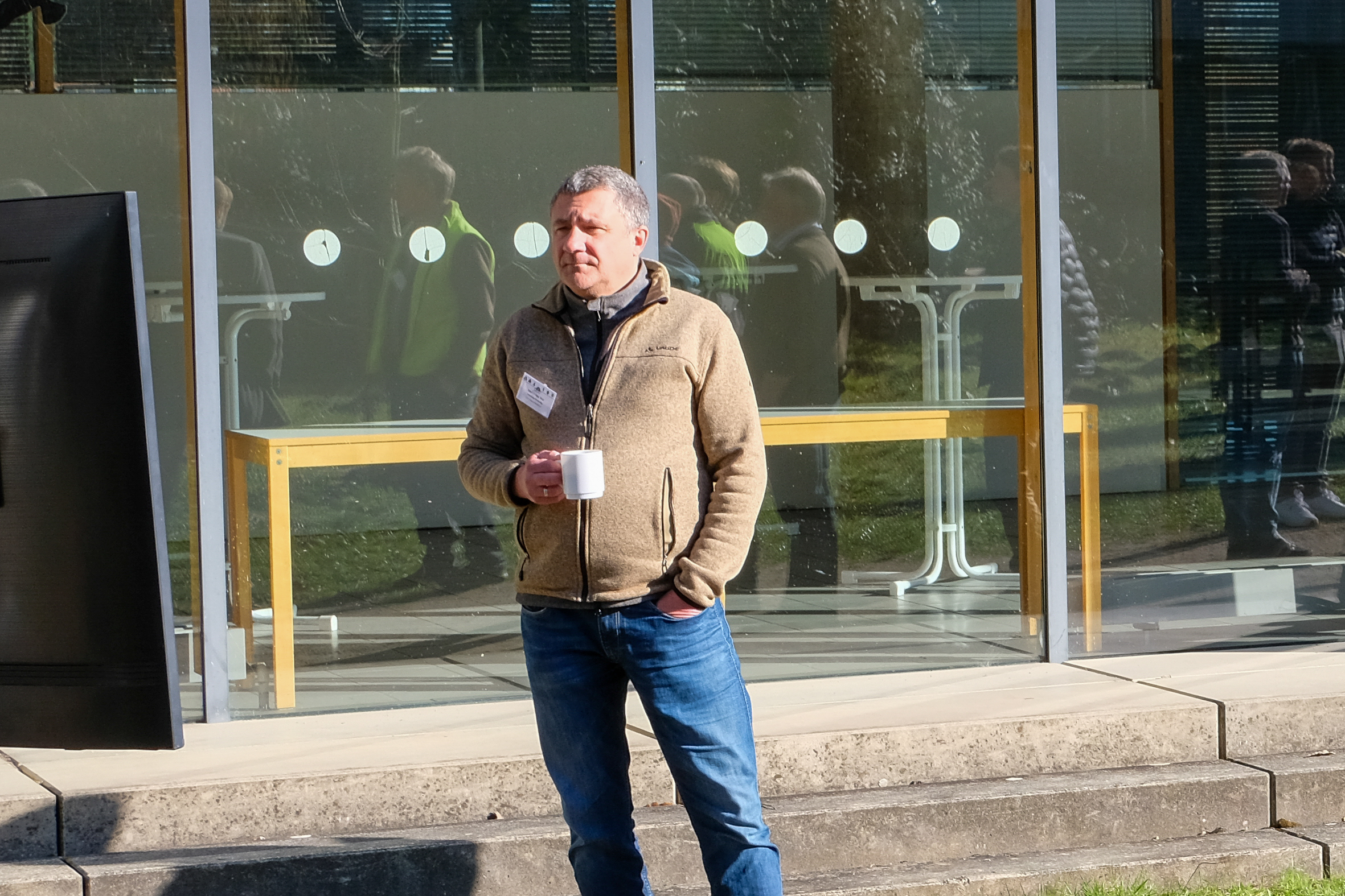 A participant enjoys the sunlight and a hot drink whilst awaiting an outdoor presentation at SmartForest 2026